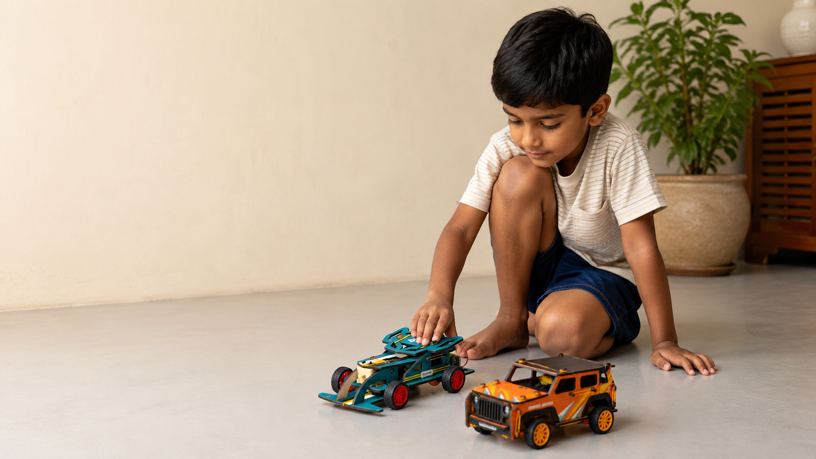 A ten year old boy sitting cross-legged on the floor, pressing a red wheel onto a half-built wooden Clapstore race car kit, loose parts around him